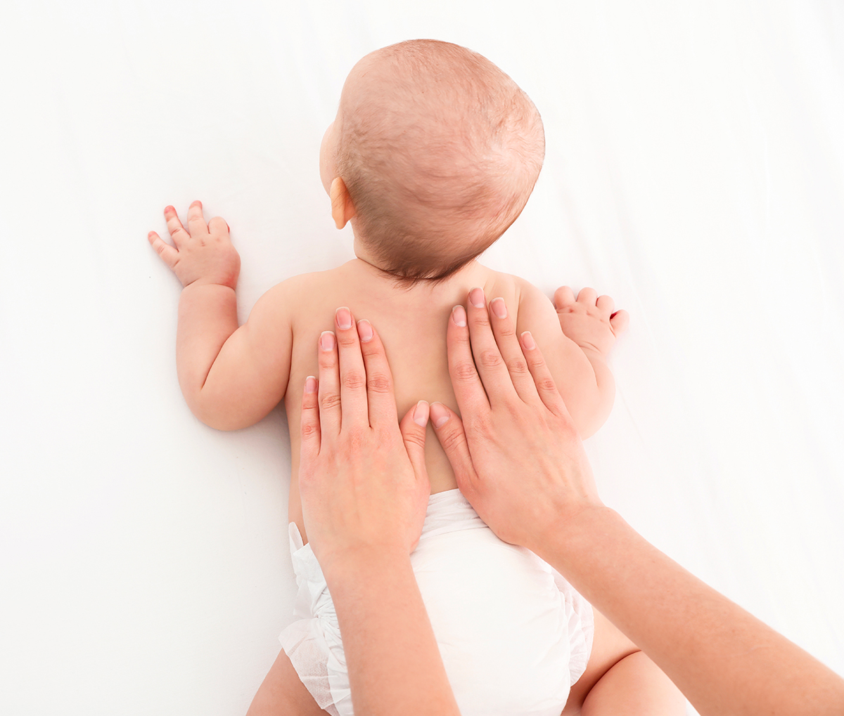 Un bébé souriant pendant une séance de massage, accompagné par sa maman